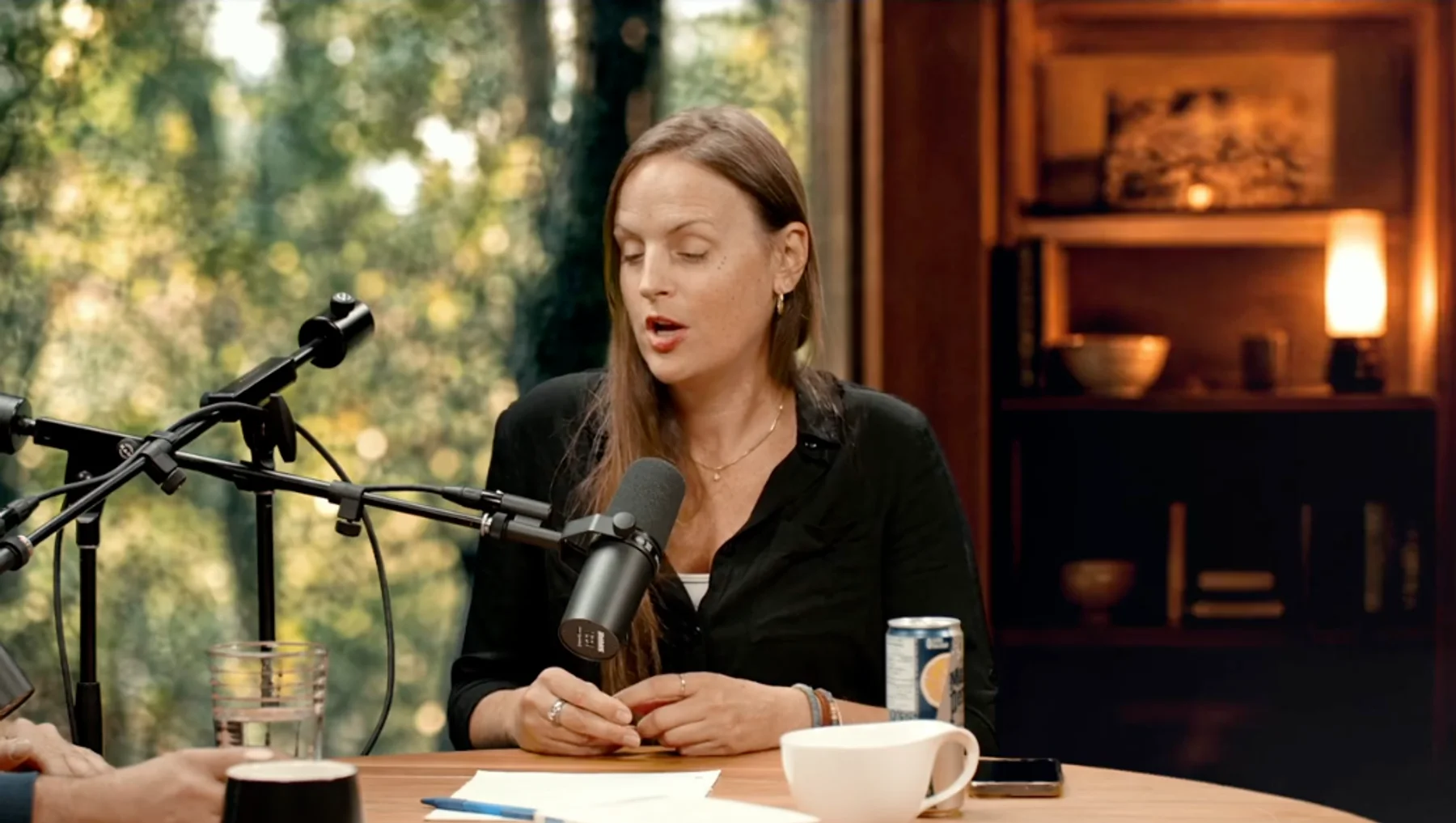 Image d'un podcast enregistré au studio : l'animatrice au micro, le décor incrusté en direct